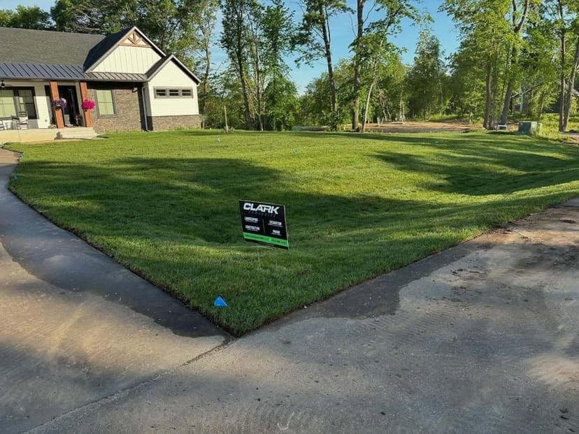 Freshly laid sod in a residential yard with a sign for Clark Landscaping services.