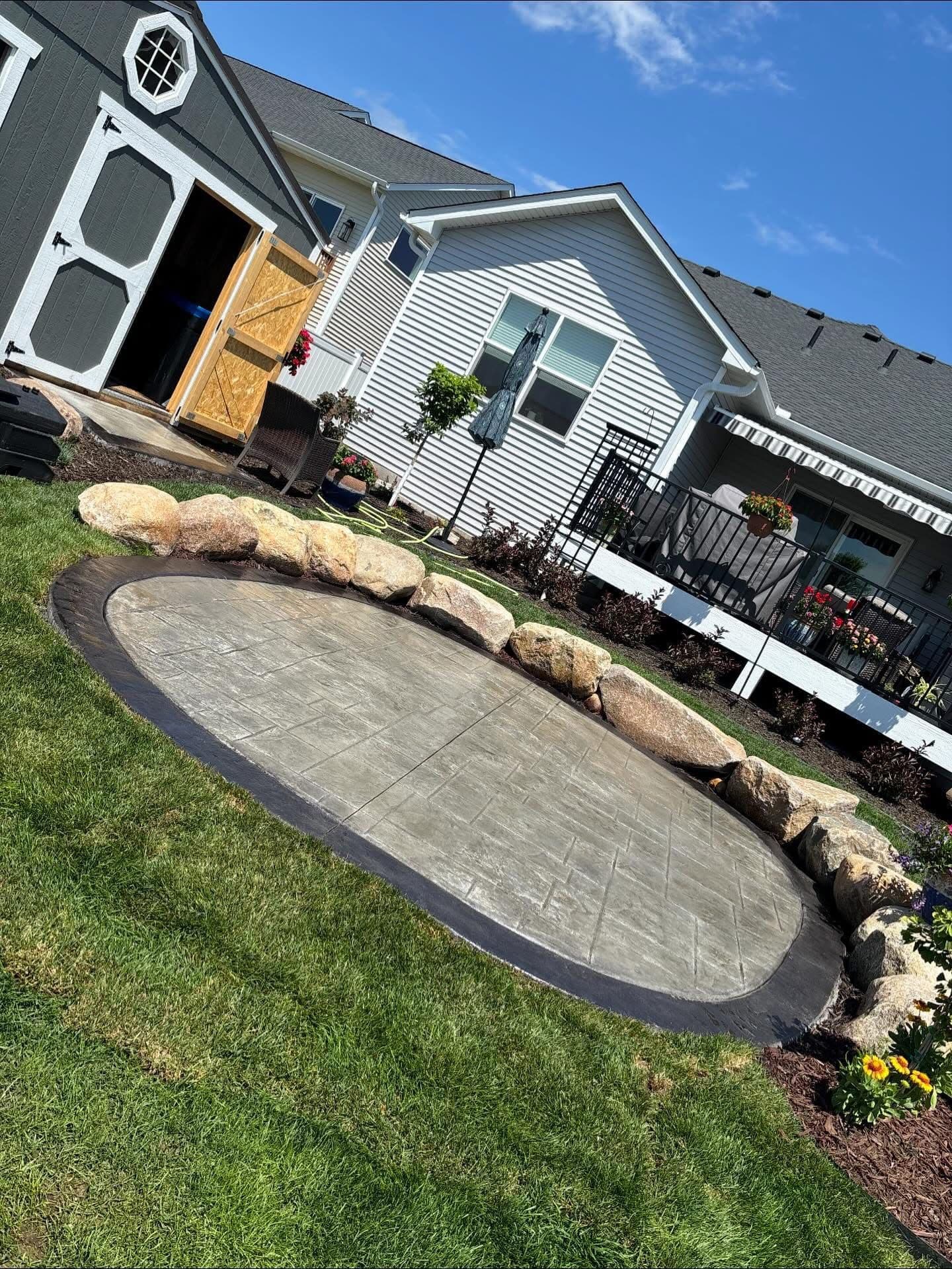 Stamped Concrete Patio with Boulder Border and Fresh Plantings image